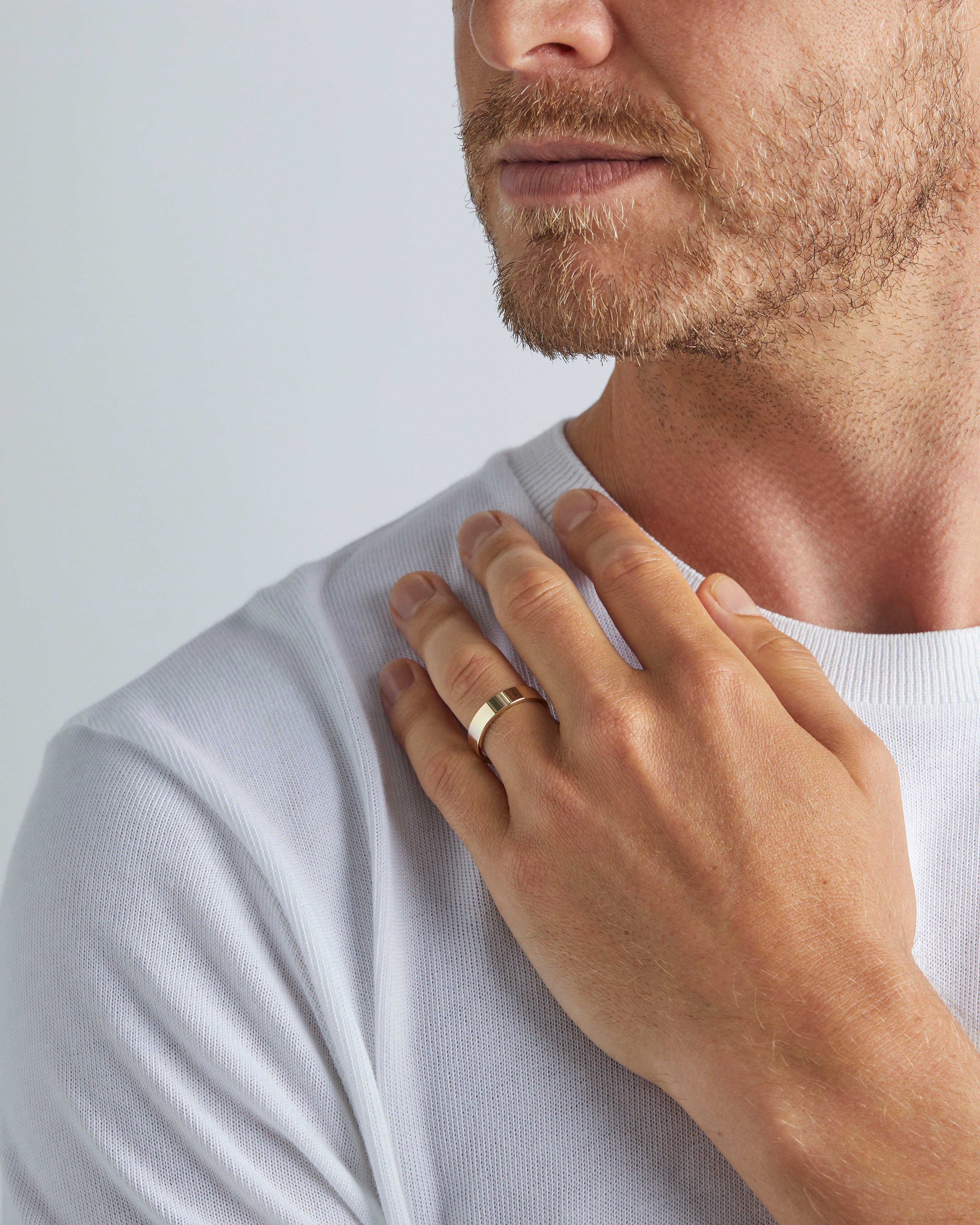 A model wears our 5mm flat wedding ring in yellow gold