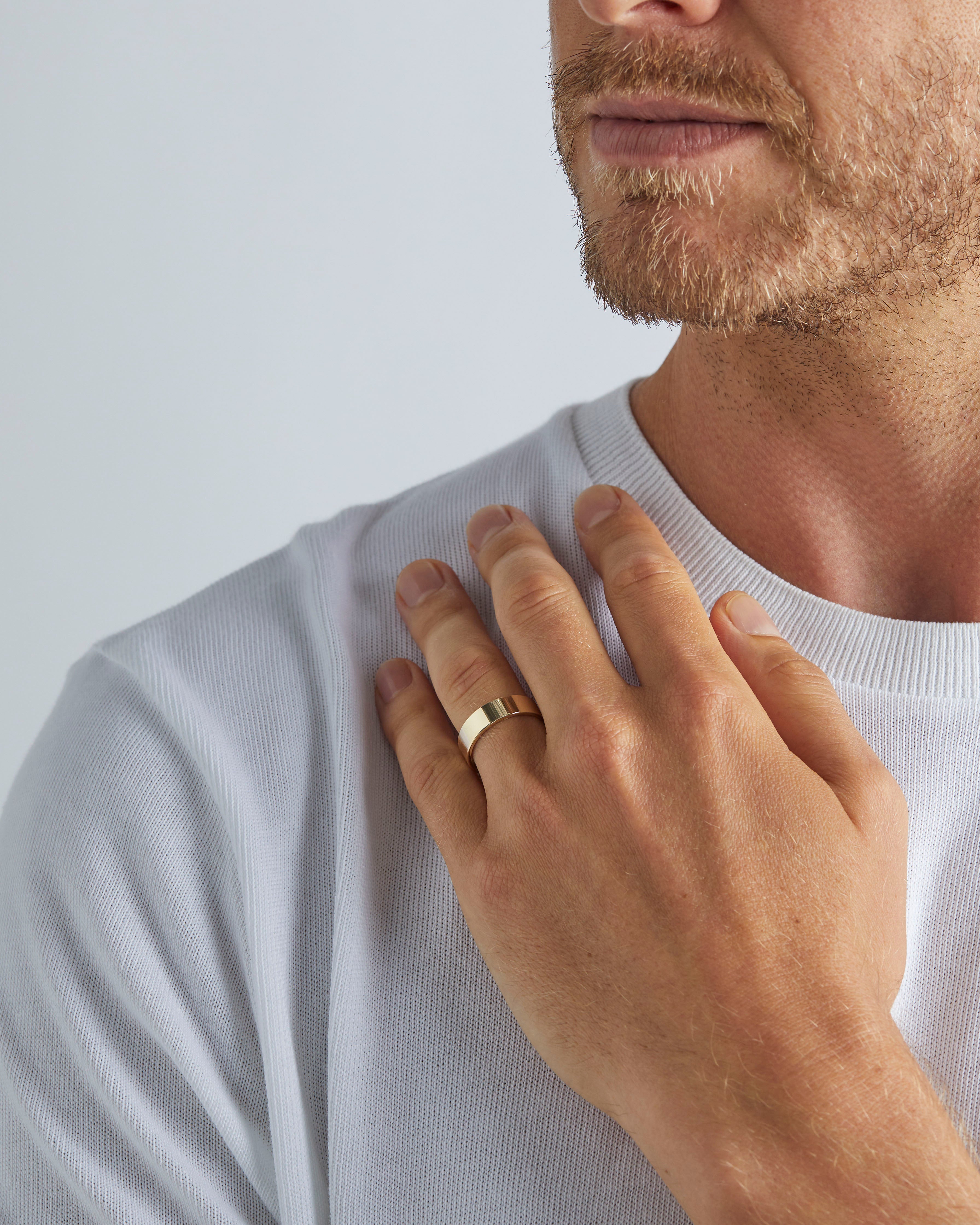 A model wears our 6mm flat wedding ring in yellow gold