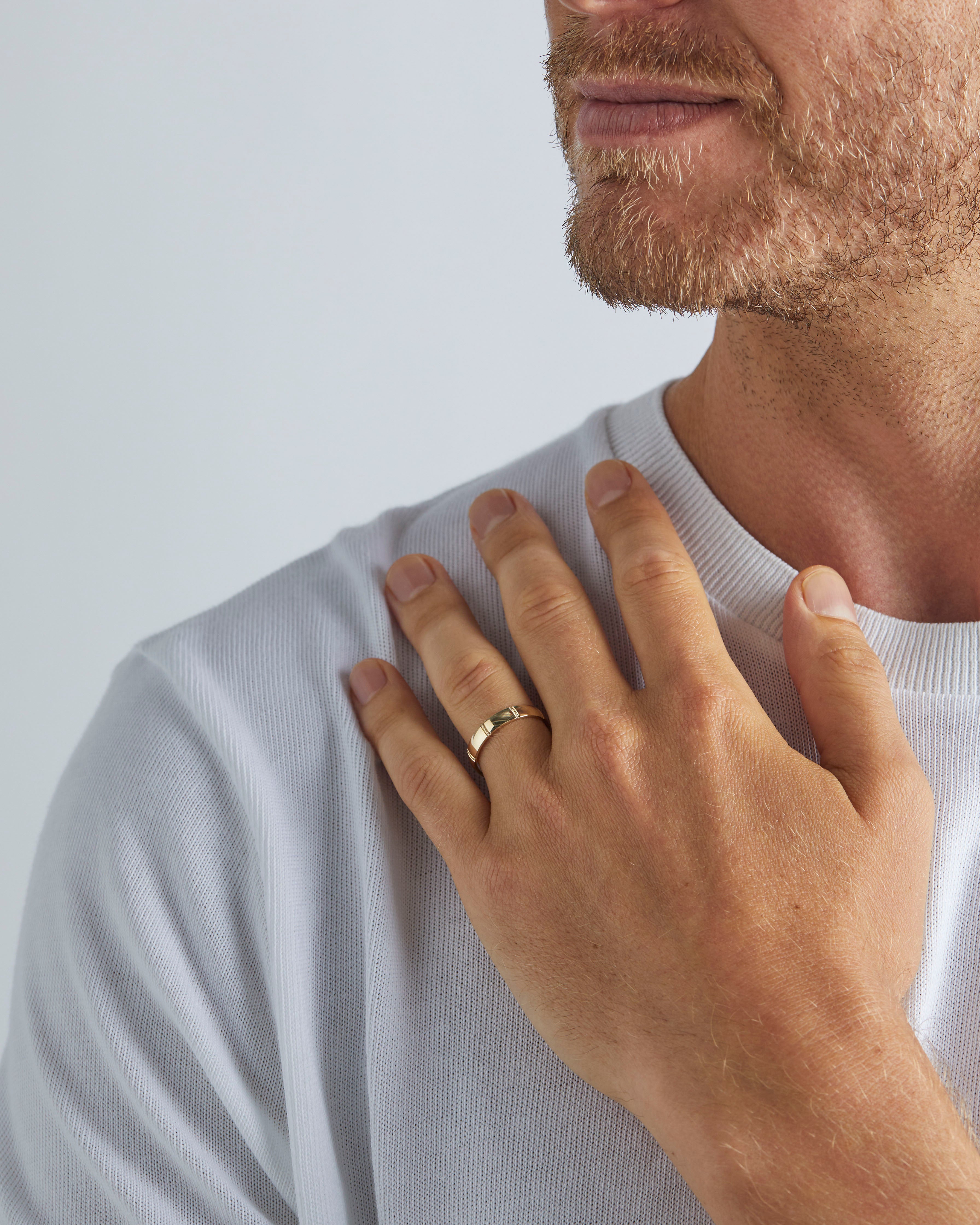 A model wears our 4mm grain wedding ring in yellow gold