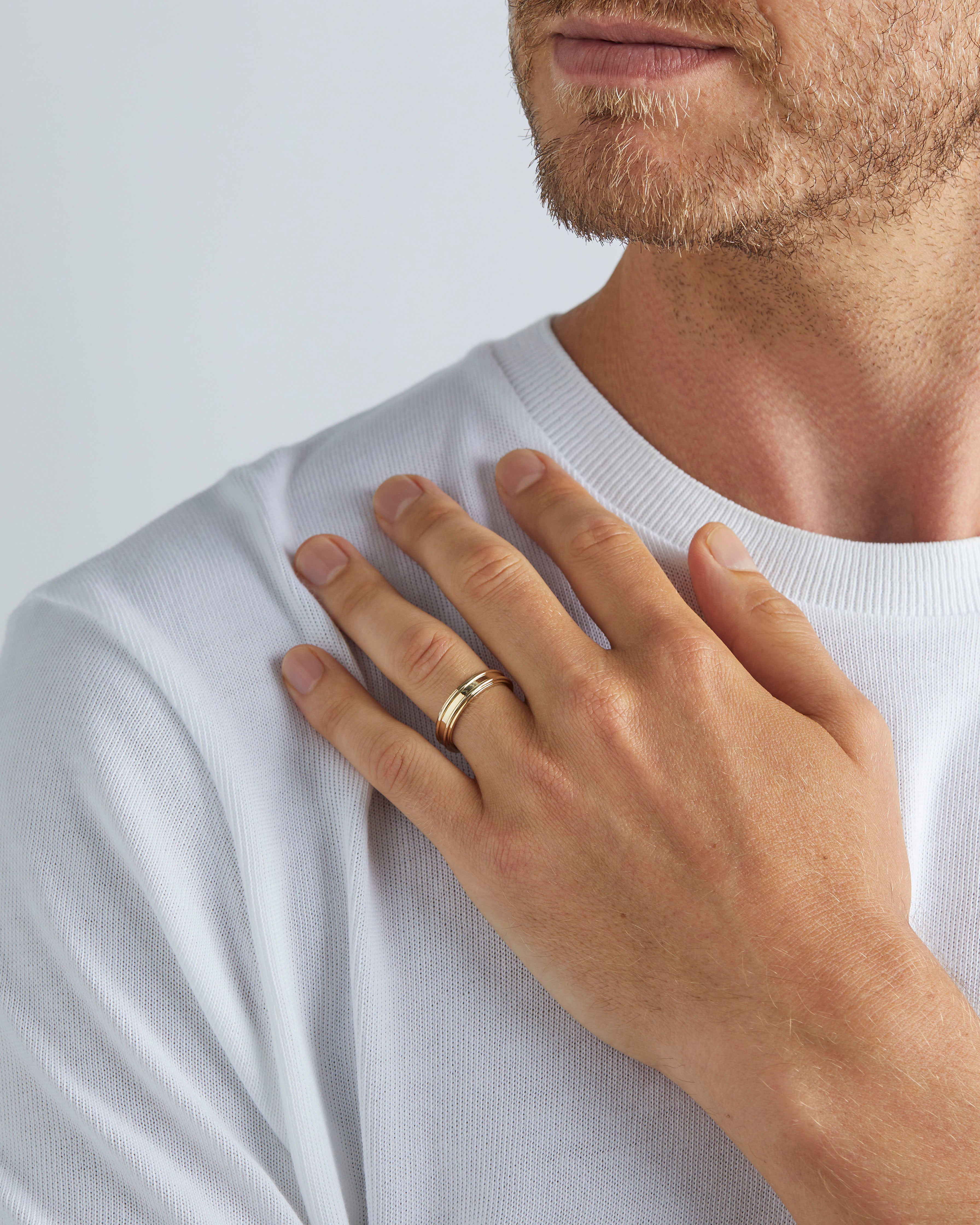 A model wears our 5mm border wedding ring in yellow gold