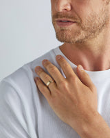 A model wears our 6mm border wedding ring in yellow gold
