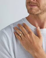 A model wears our 7mm border wedding ring in yellow gold