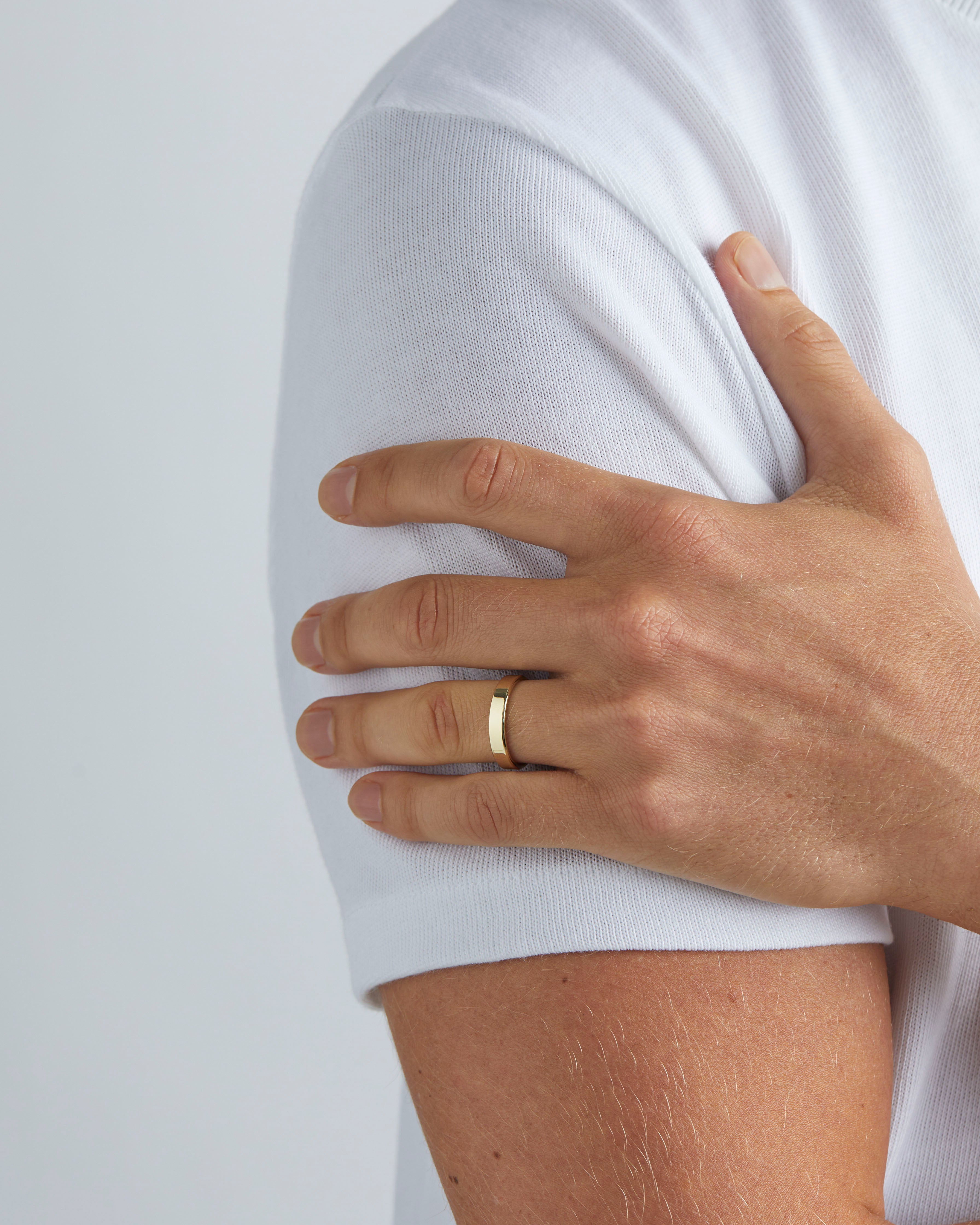 A model wears our 4mm chamfered wedding ring in yellow gold