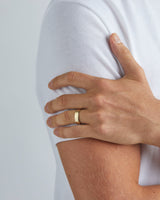 A model wears our 6mm chamfered wedding ring in yellow gold