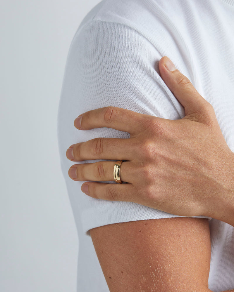 A model wears our 6mm surge wedding ring in yellow gold