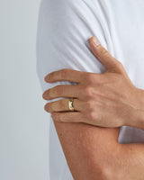 A model wears our 7mm surge wedding ring in yellow gold