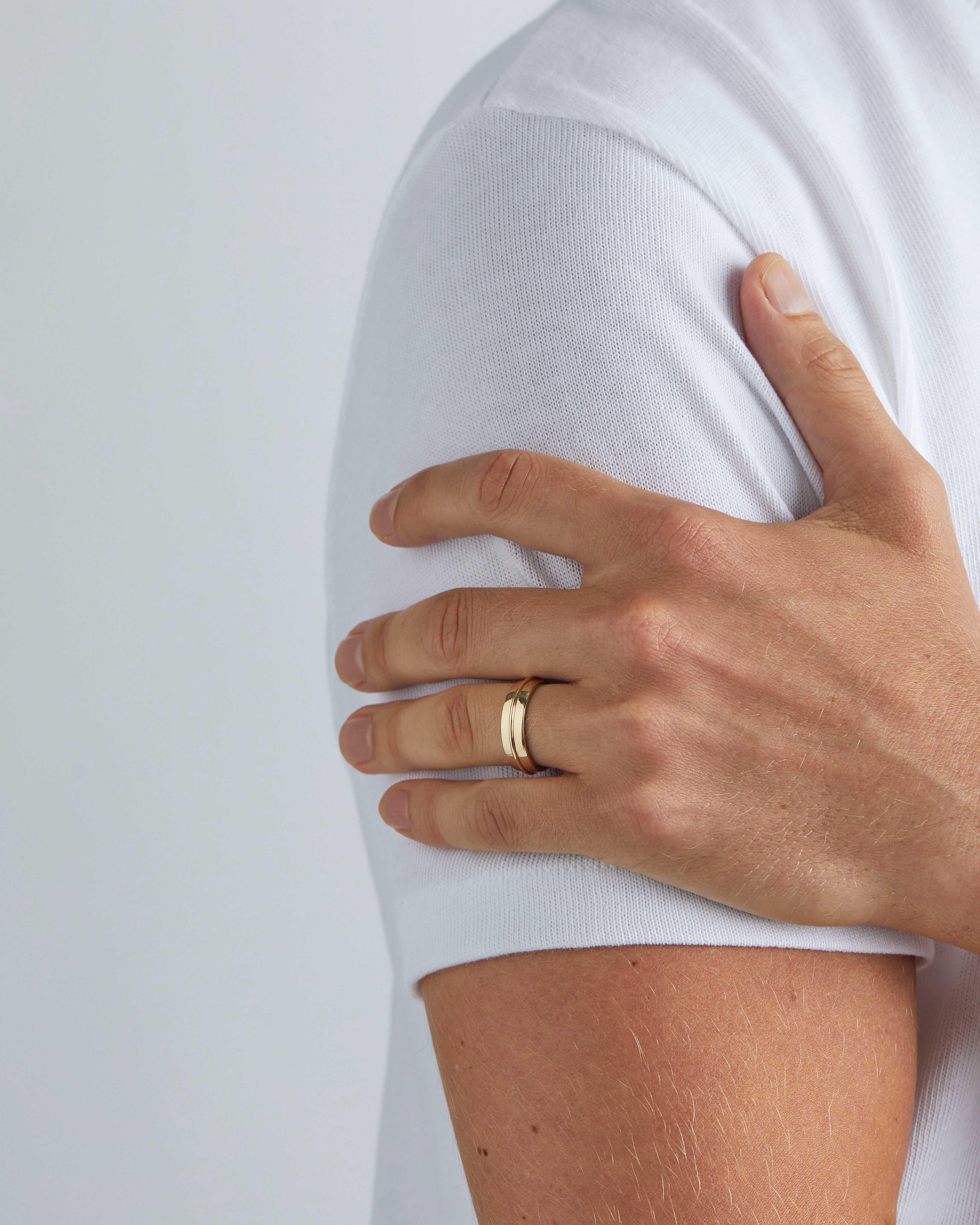 A model wears our 6mm seam wedding ring in yellow gold