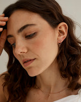 A woman wearing the Loop Through Oval Studs in rose gold.