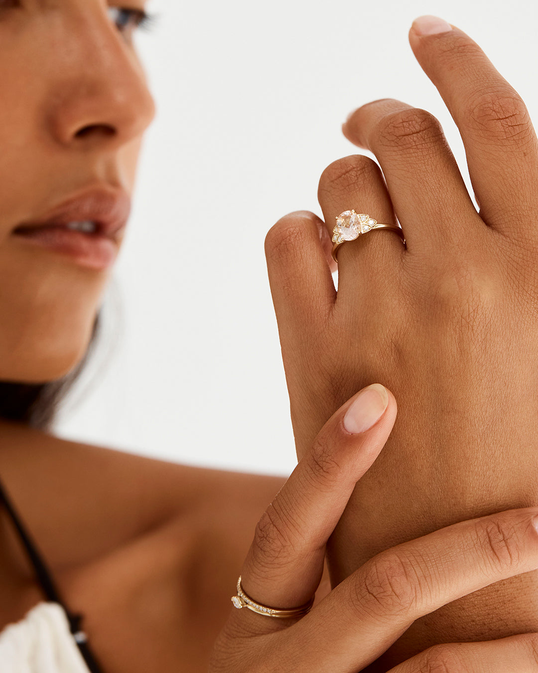 A model wears our oval morganite engagement ring, adorned with white diamonds either side