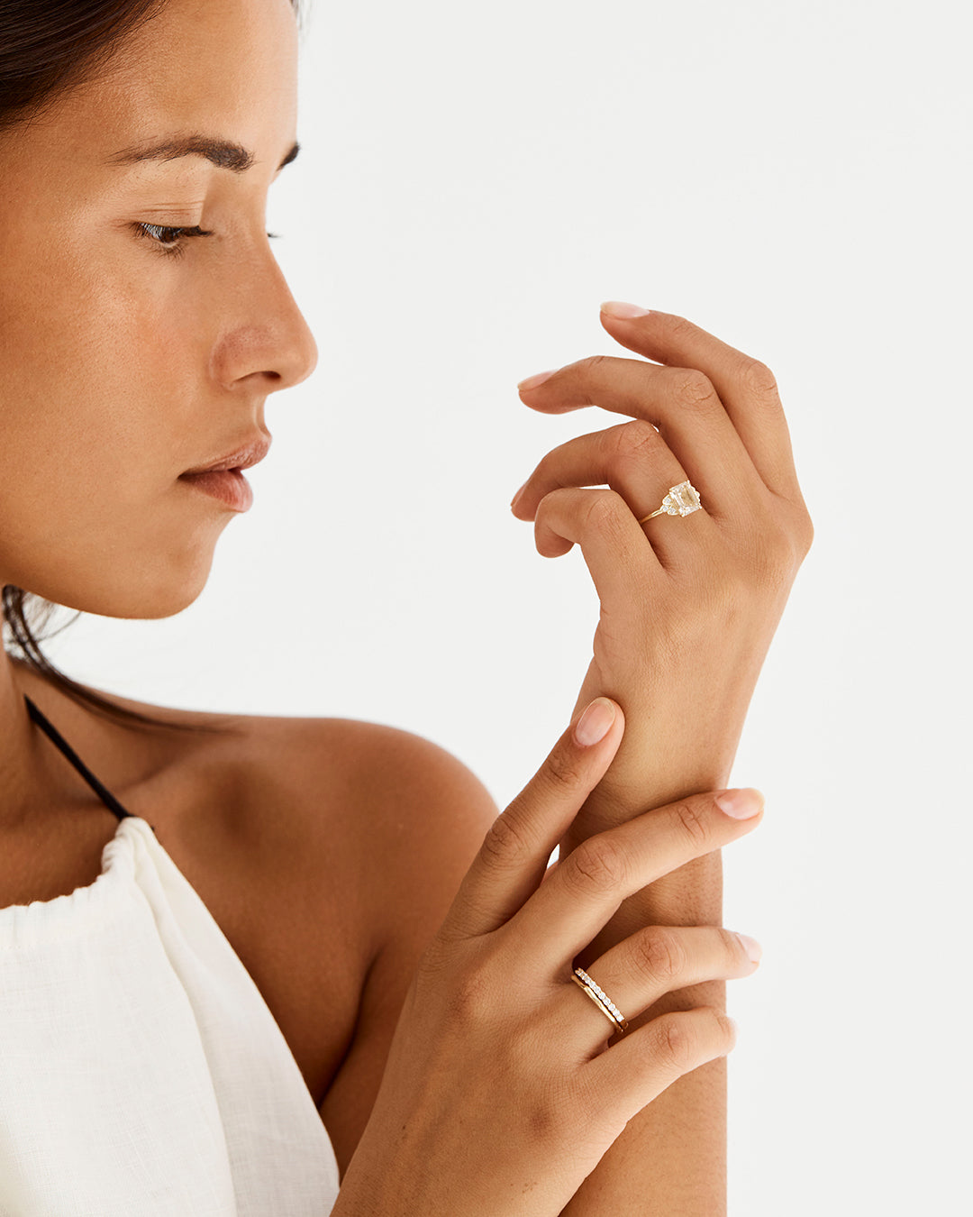 A model wears an emerald cut rutilated quartz engagement ring, adorned with white diamonds either side