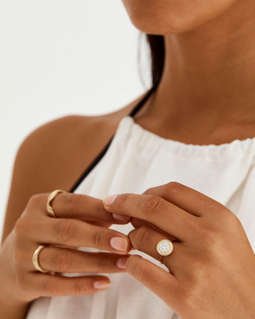 A model wears a classic white diamond halo engagement ring