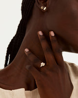 A model wears an emerald cut engagement ring, with trillion cut white diamonds either side