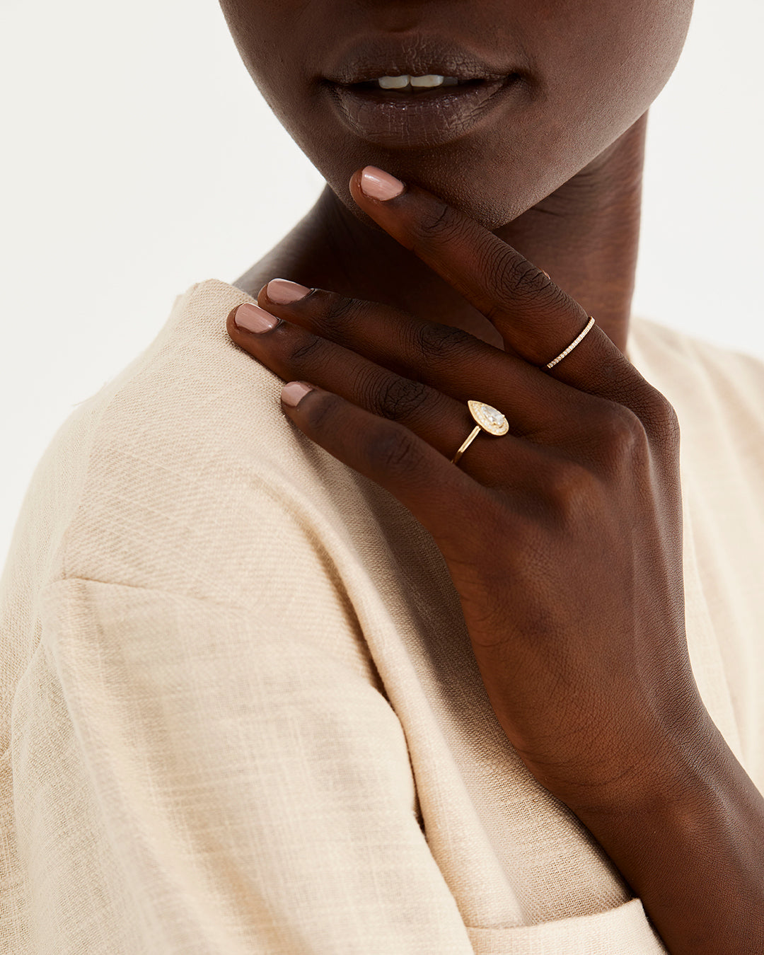 A model wears a pear cut white diamond halo engagement ring 