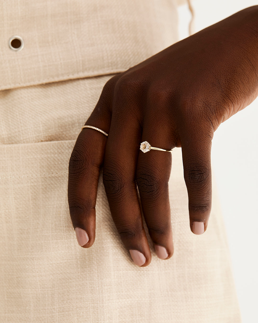 A solitaire style engagement ring featuring a rutilated quartz, worn by a model 