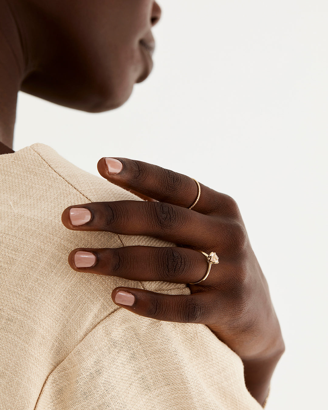 A solitaire style engagement ring featuring a morganite, worn by a model 