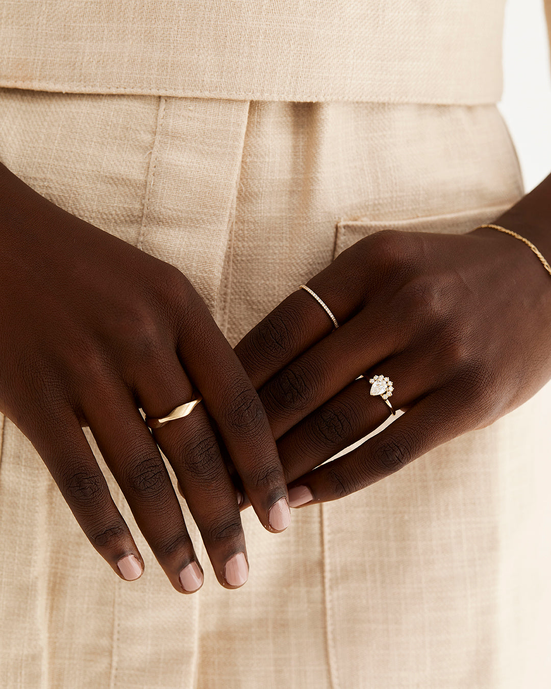 A pear cut diamond is set with a half-halo of white diamonds, worn by a model