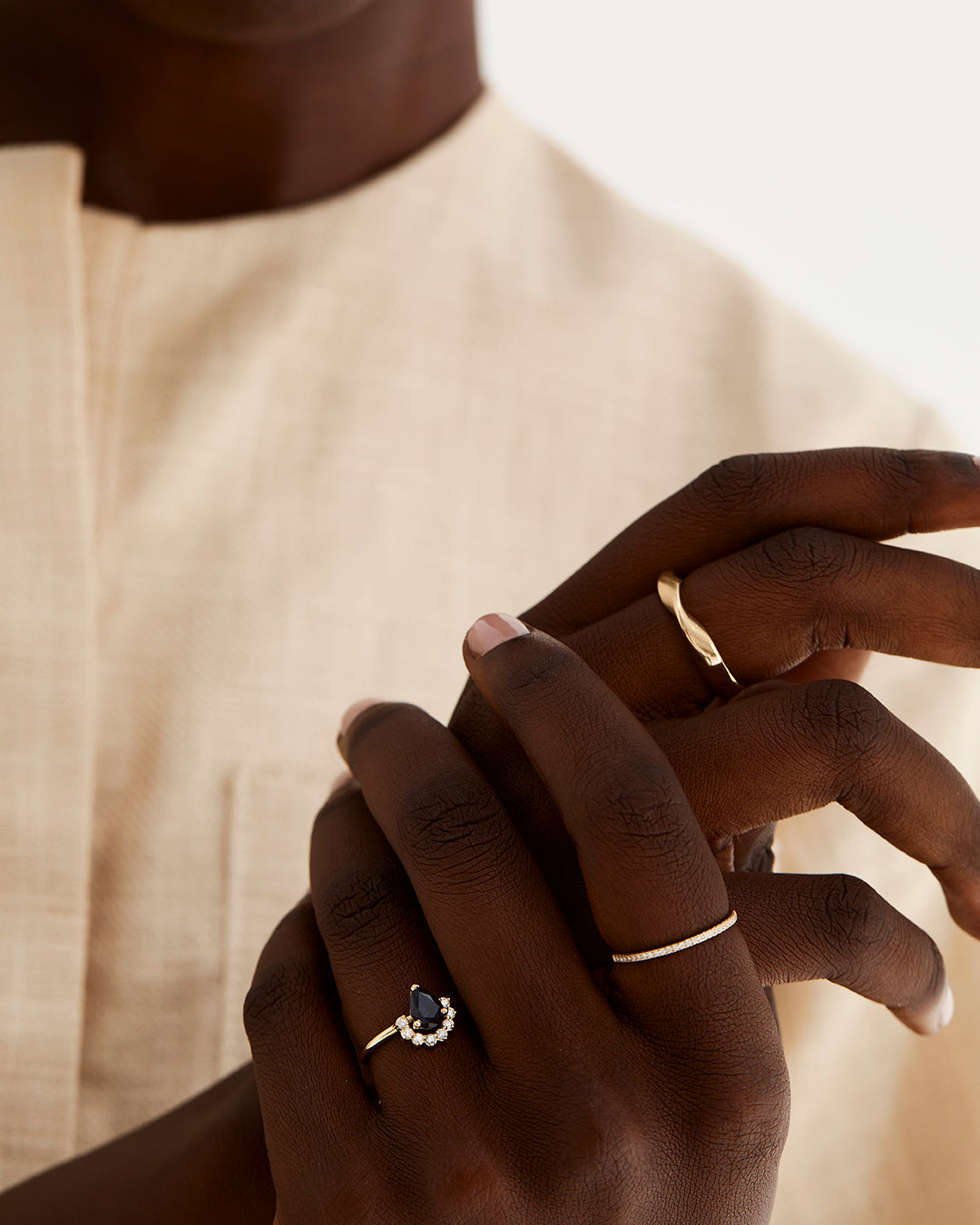 A pear cut Australian sapphire is set with a half-halo of white diamonds, worn by a model