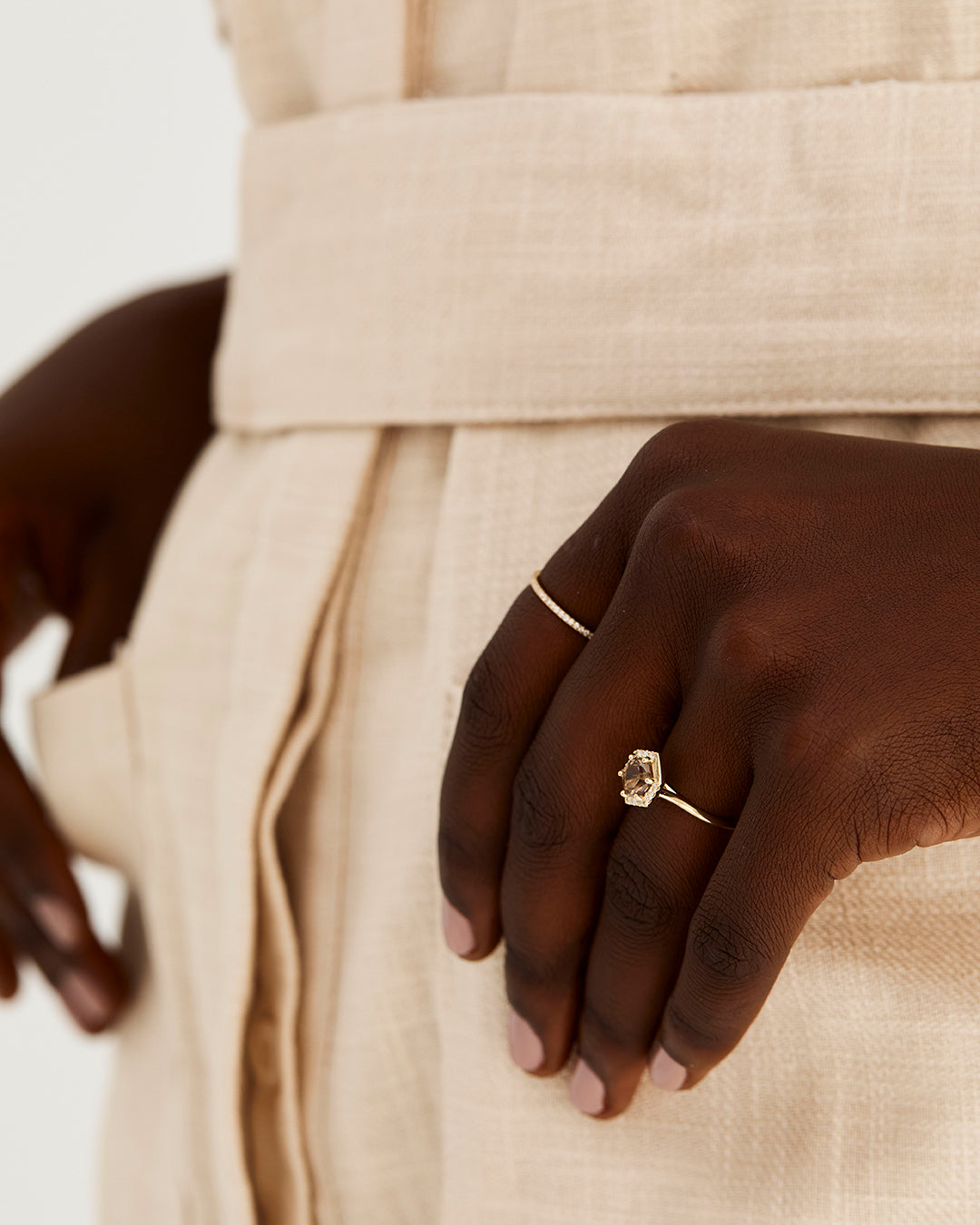 A model wears a hexagonal cut smokey quartz, surrounded by a halo of white diamonds