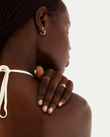 A model wears a round trio style engagement ring with a rutilated quartz surrounded by white diamond either side