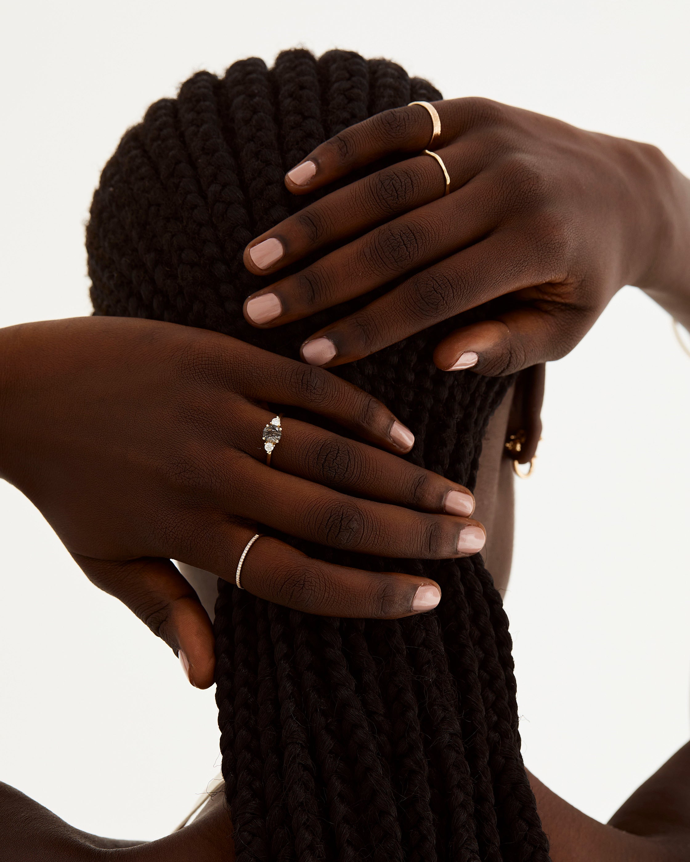 A model wears a round trio style engagement ring with a tourmalinated quartz surrounded by white diamond either side