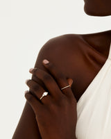 A model wears a round trio style engagement ring with a white diamond surrounded by white diamond either side