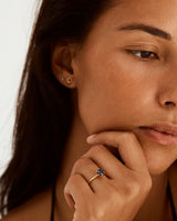 A model wears a solitaire style engagement ring, featuring a round cut Australian sapphire, with diamonds in and around the setting