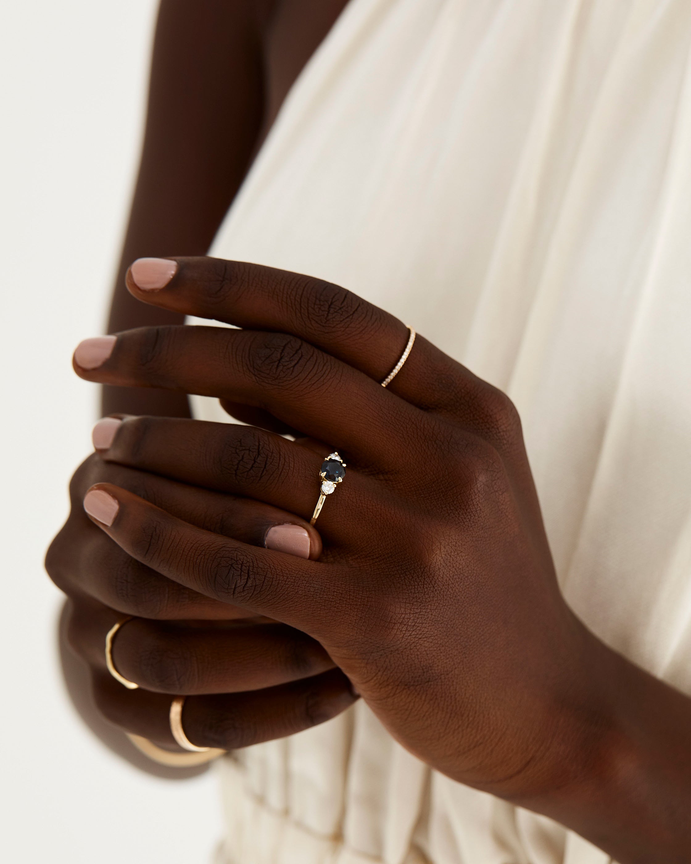 A model wears a round trio style engagement ring with a Australian Sapphire surrounded by white diamond either side