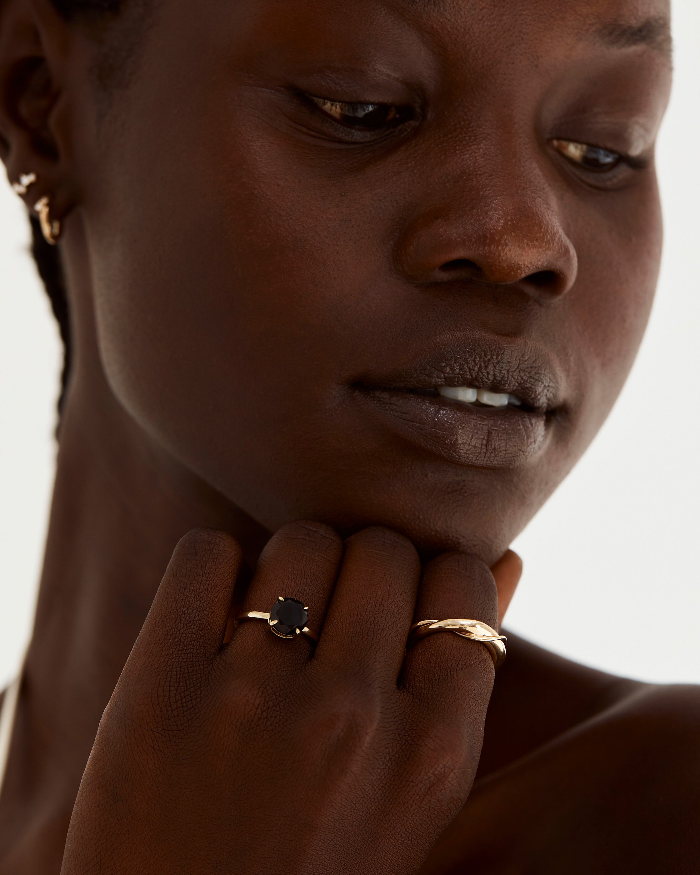 A model wears a round solitaire featuring an 8mm black spinel