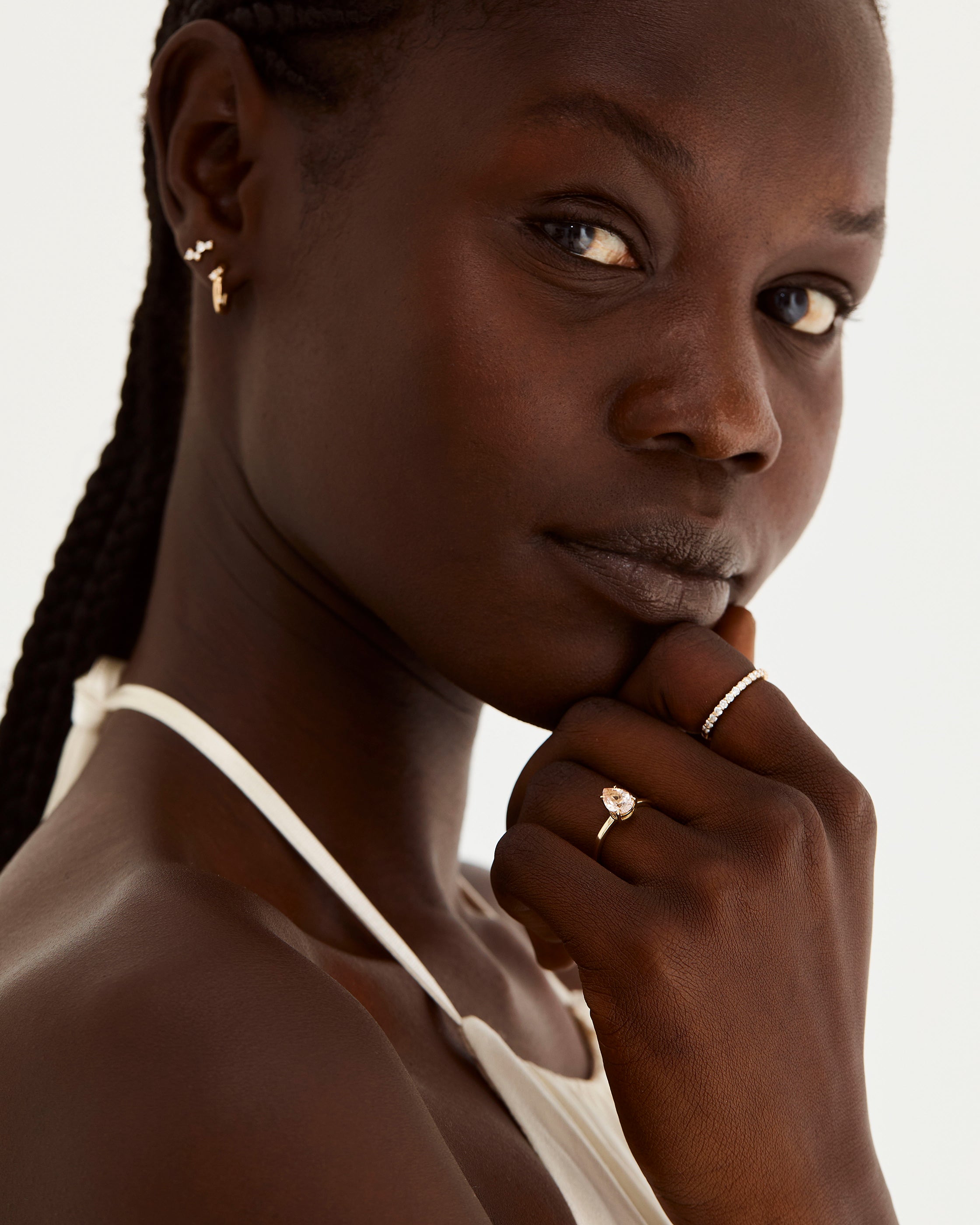 A model wears a pear cut solitaire featuring a soft pink morganite