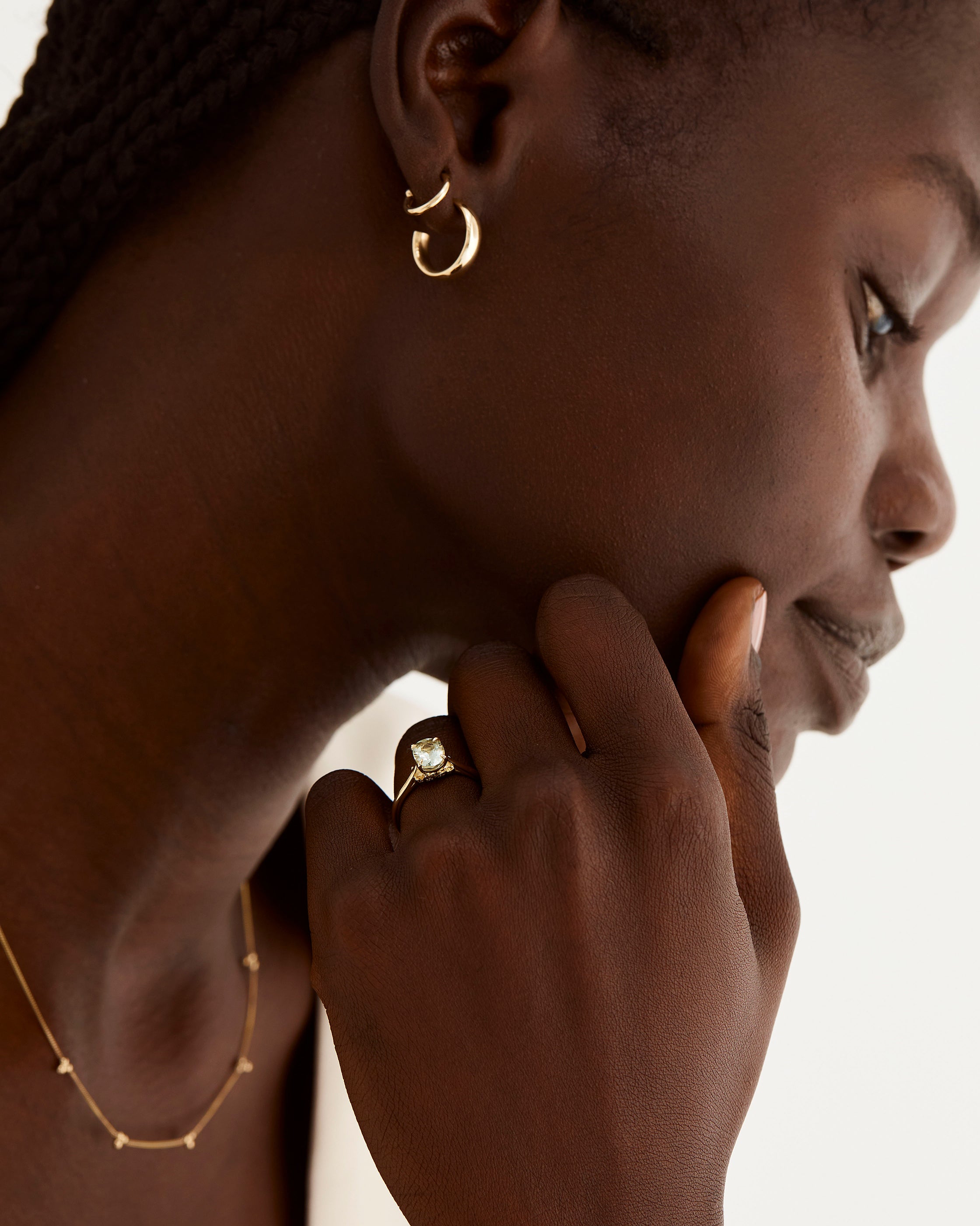 A model wears a oval solitaire with a green amethyst and diamond details in the setting