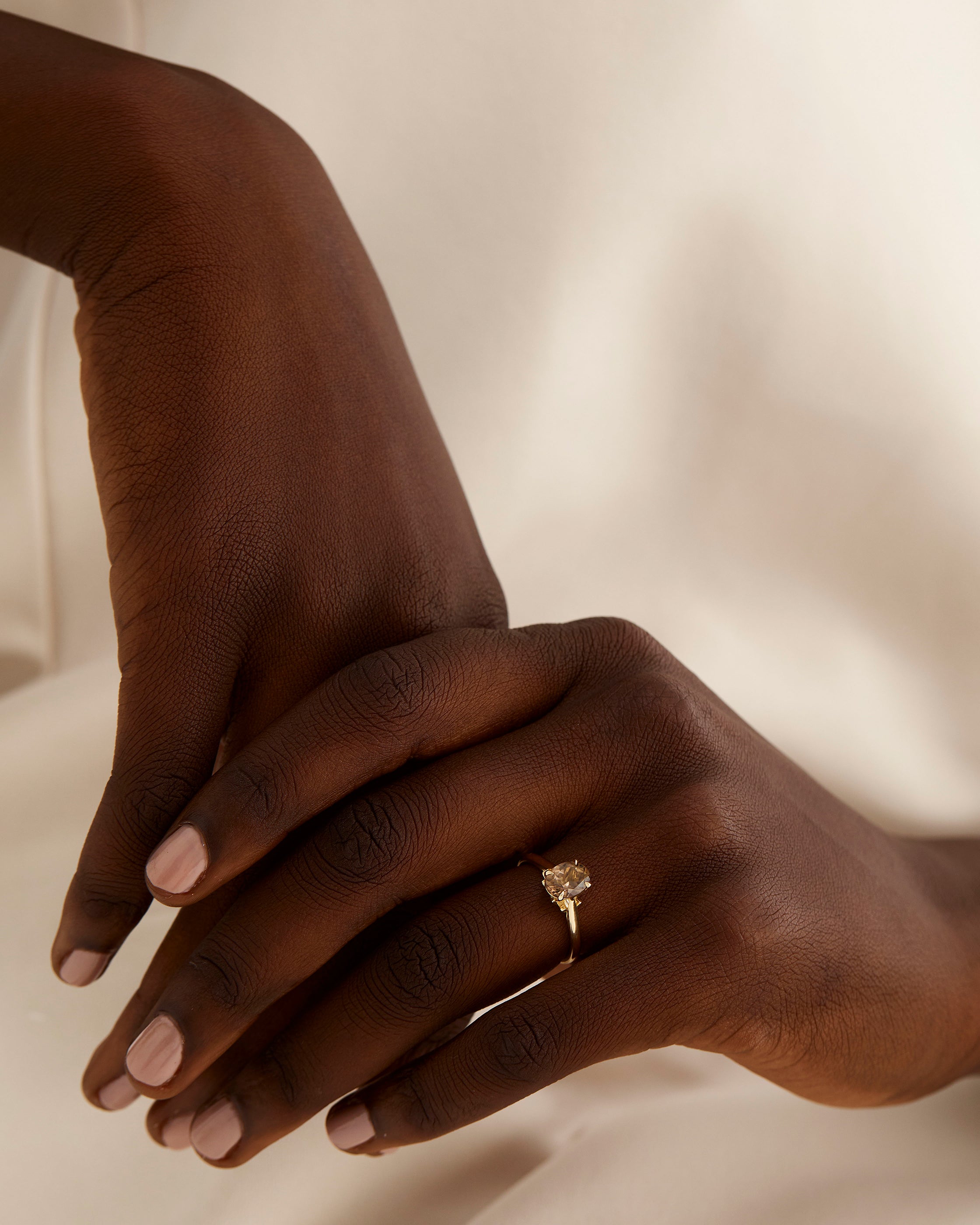 A model wears a oval solitaire with a smokey quartz and diamond details in the setting
