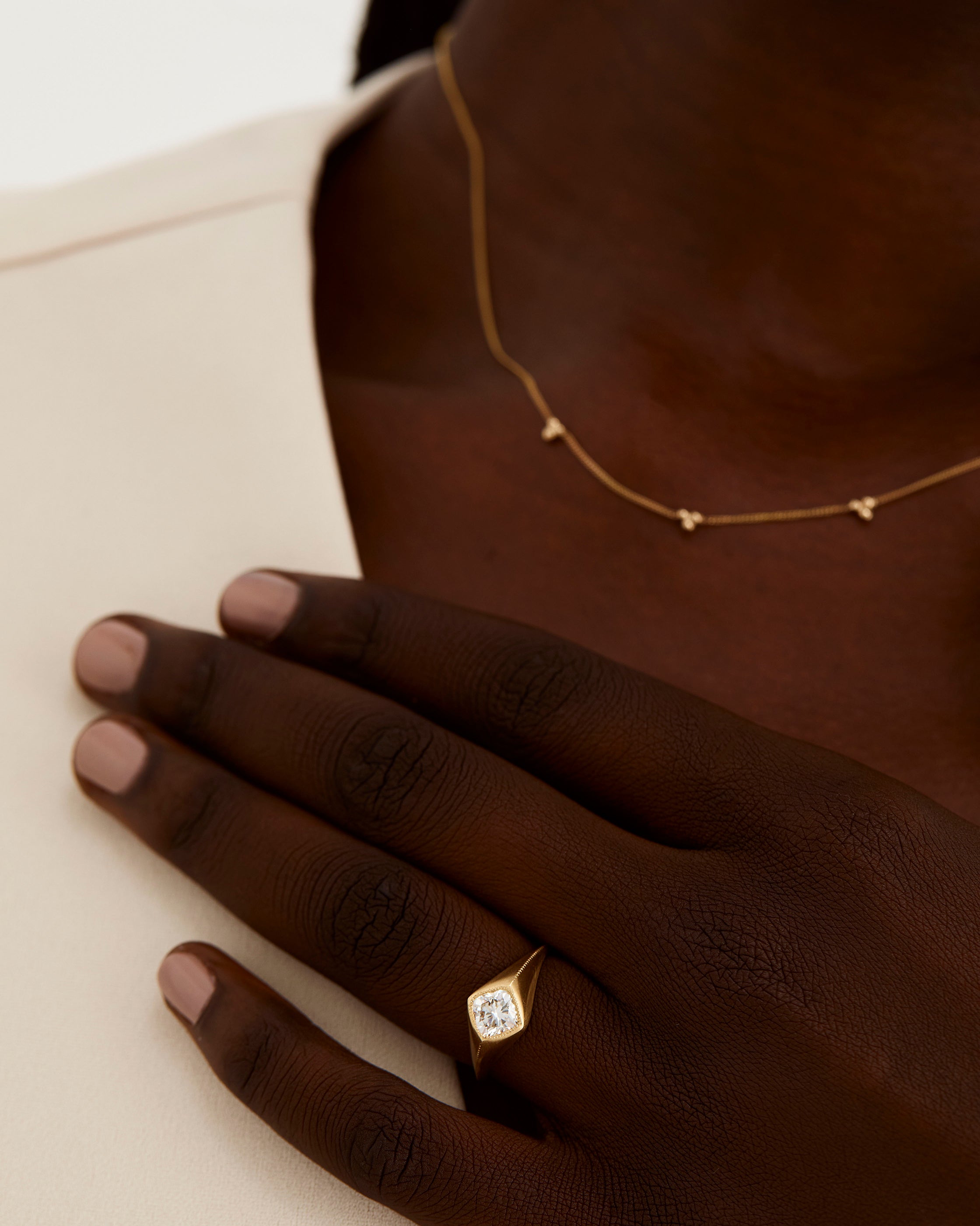 A model wears a cushion cut white diamond set in a traditional signet style