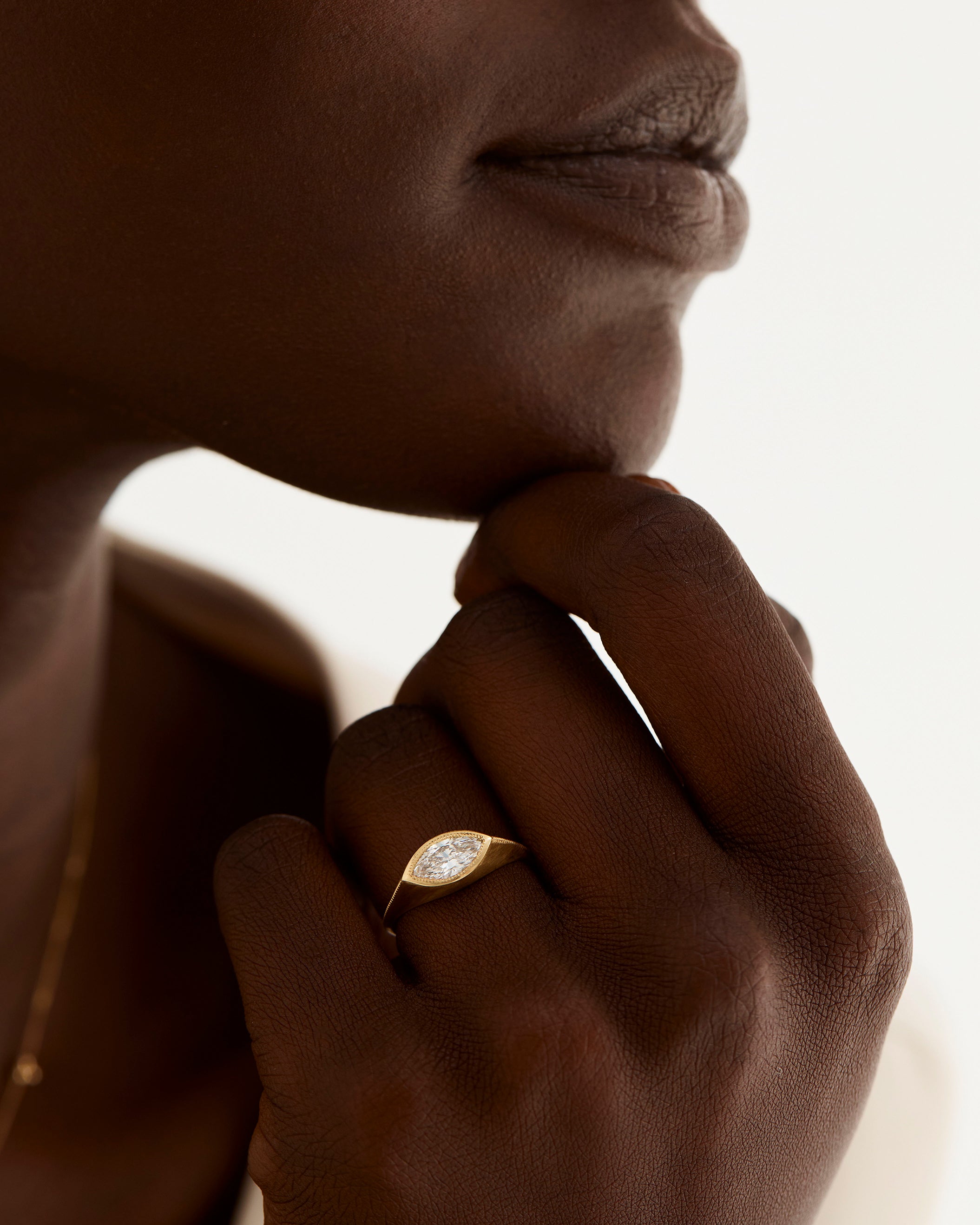 A model wears a marquise cut white diamond set in a traditional signet style