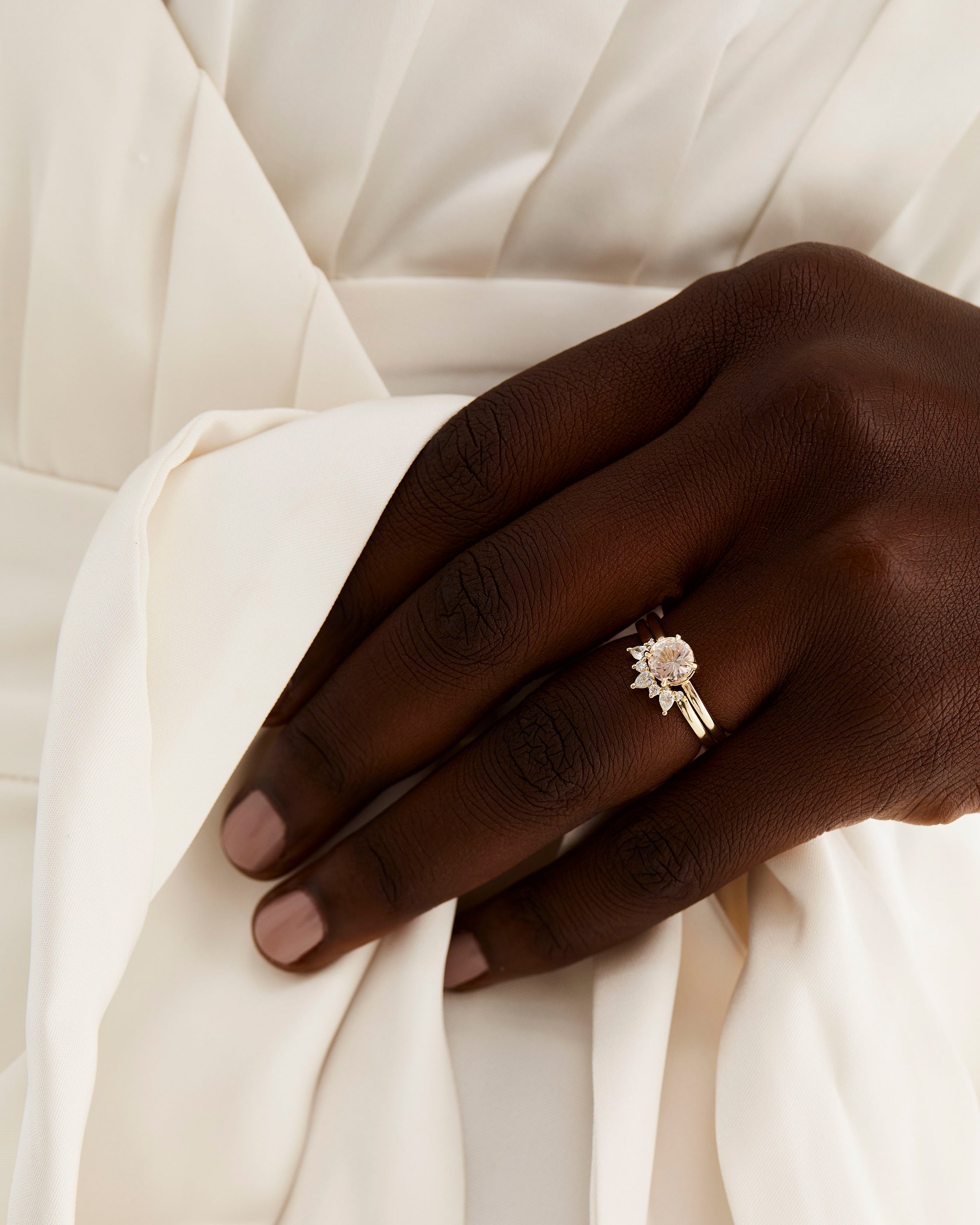 A model wears a diamond crown ring stacked with a solitaire style engagement ring