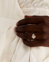 A model wears a diamond crown ring stacked with an oval solitaire style engagement ring