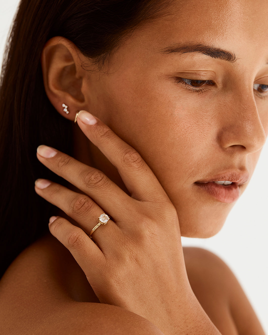 A model wearing a round solitaire style engagement ring featuring a rutilated quartz. 