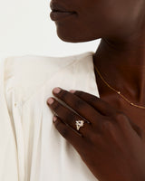 A model wears a diamond crown ring stacked with an oval solitaire style engagement ring