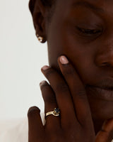 A model wears a diamond detailed crown ring stacked with a solitaire style engagement ring