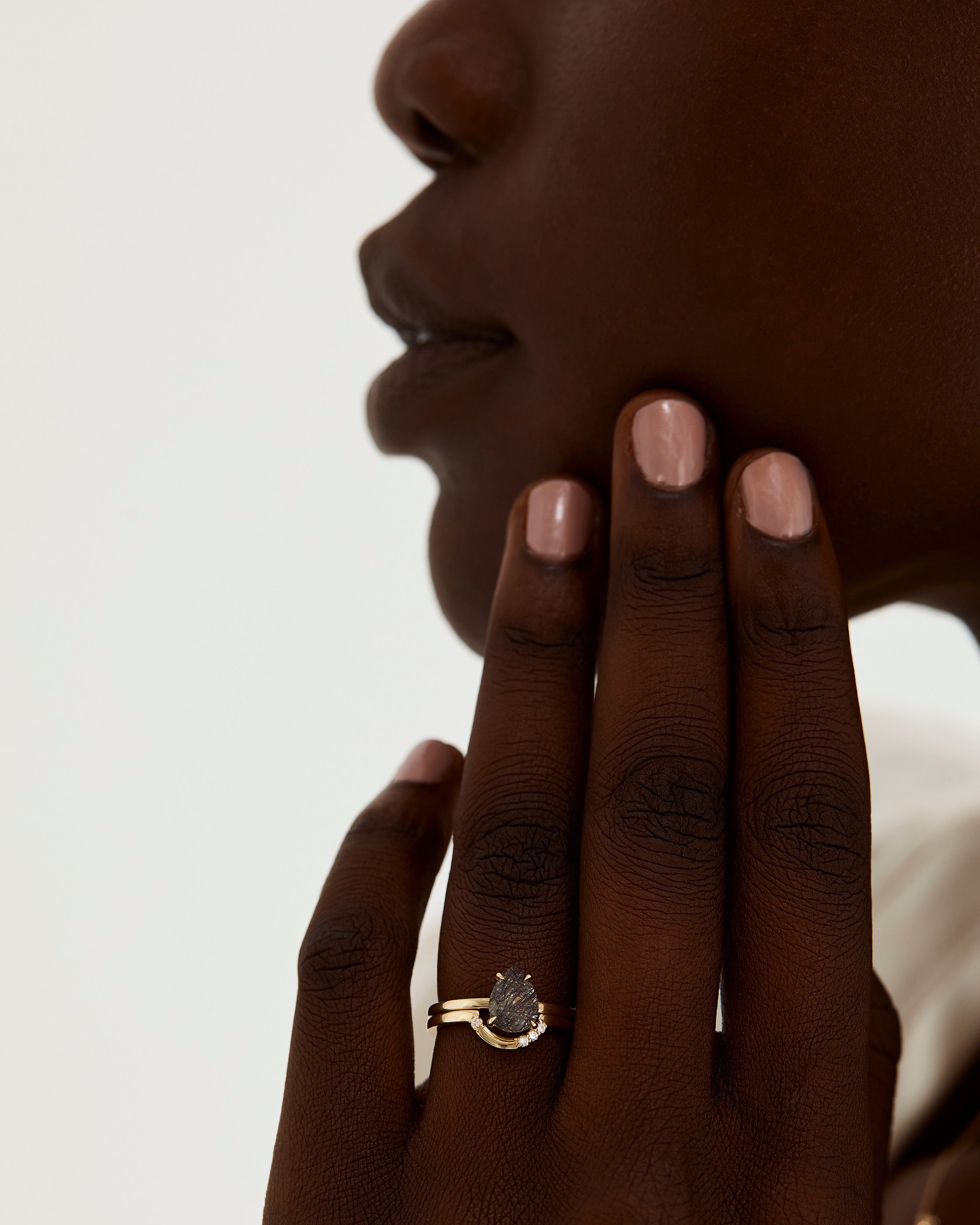 A model wears a diamond detailed crown ring stacked with a solitaire style engagement ring