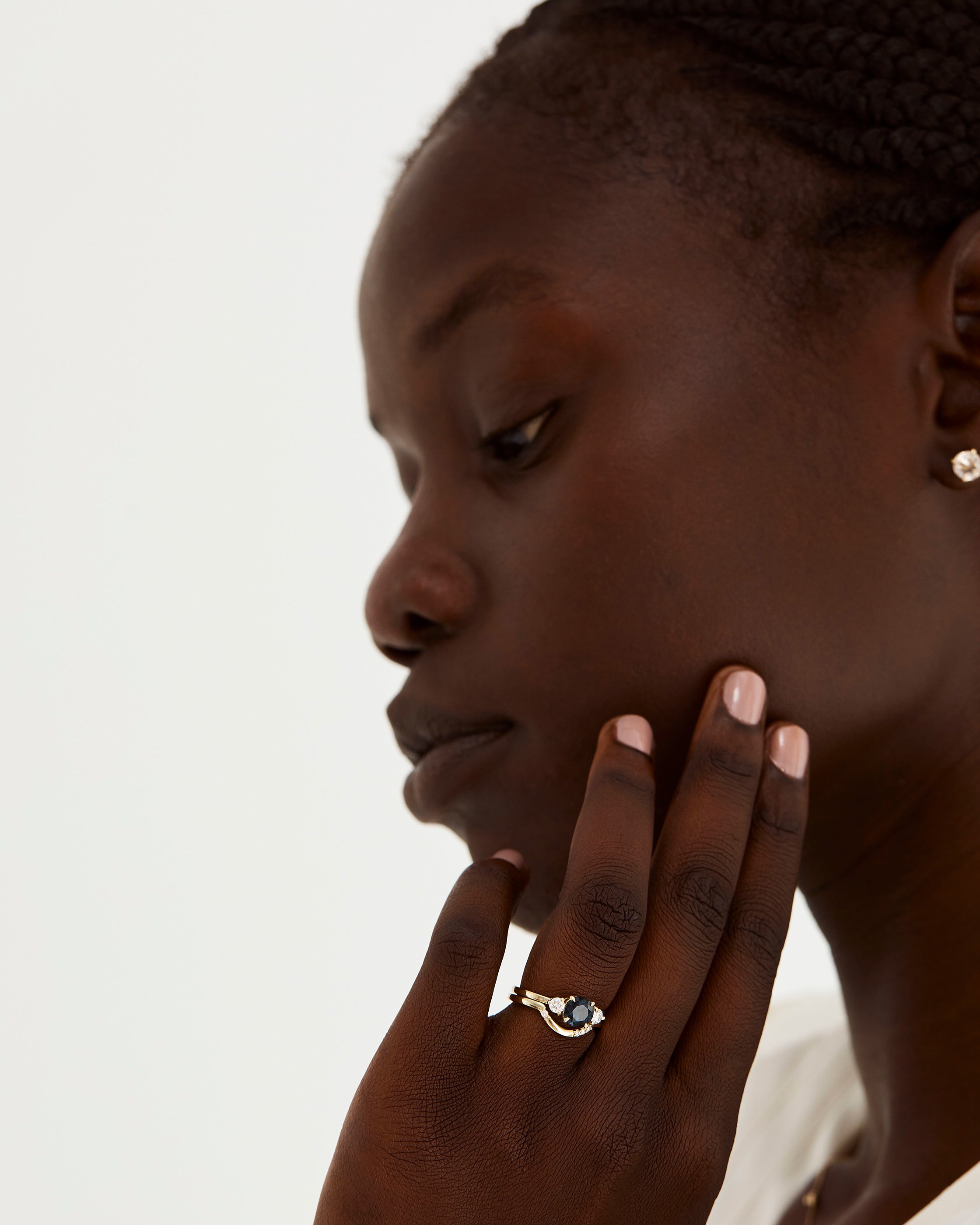 A model wears a diamond detailed crown ring stacked with a trio style engagement ring