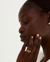 A  model wears a diamond detailed crown ring stacked with a trio style engagement ring