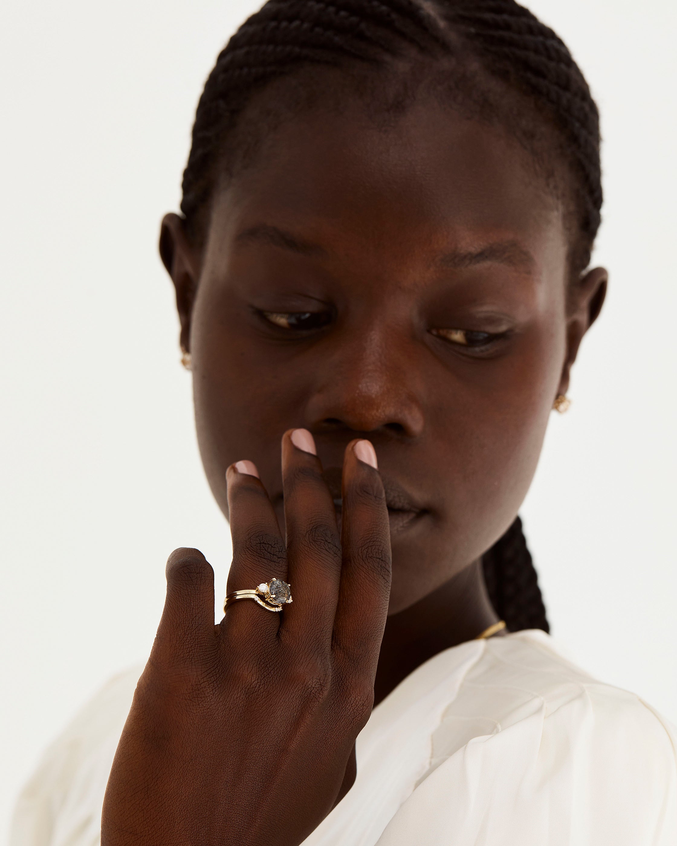 A model wears a diamond detailed crown ring stacked with a trio style engagement ring