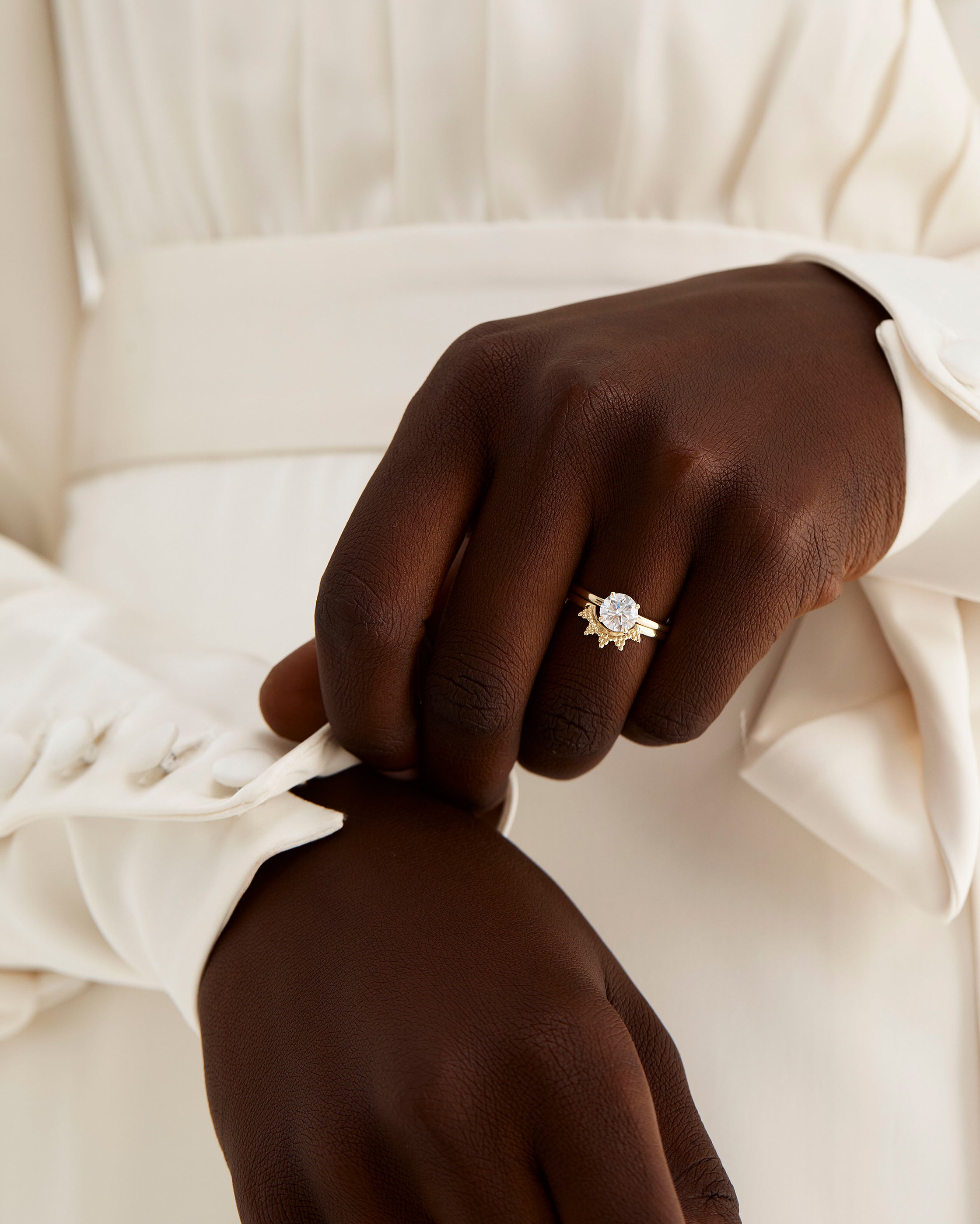 A model wears a dot detailed crown ring stacked with a solitaire style engagement ring.