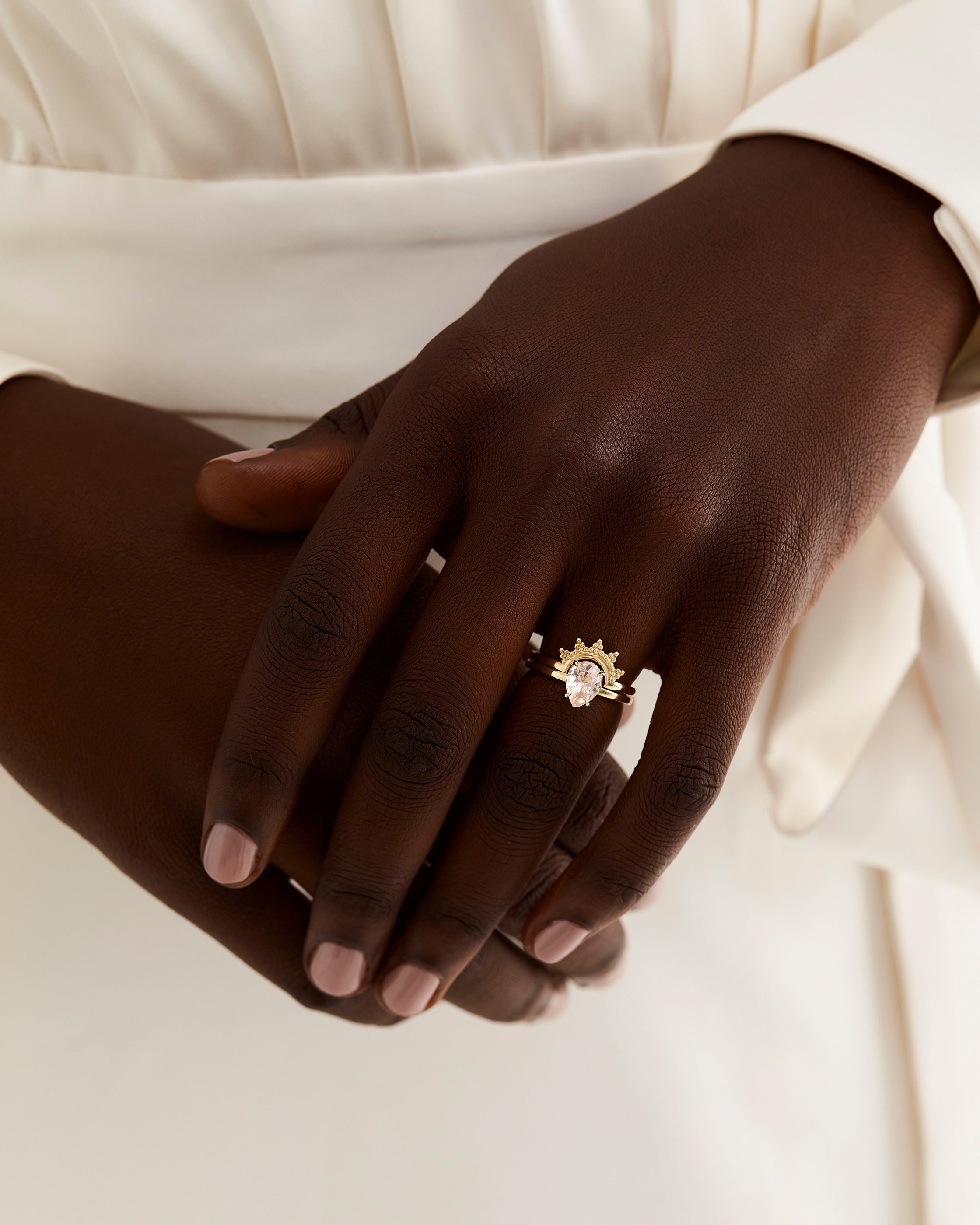 A model wears a dot detailed crown ring stacked with a solitaire style engagement ring.