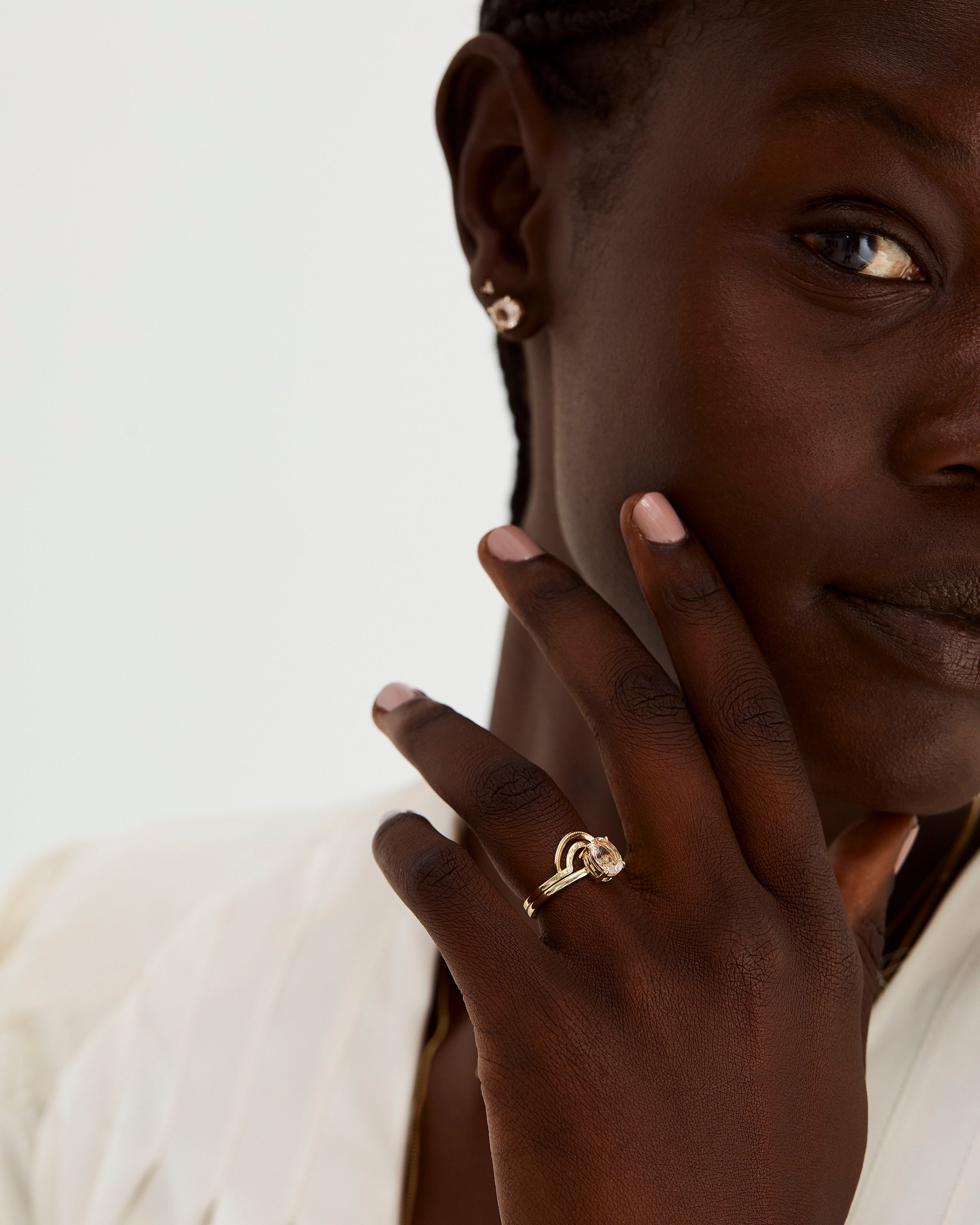 A model wears a double arc crown ring with diamonds stacked with a solitaire style engagement ring.