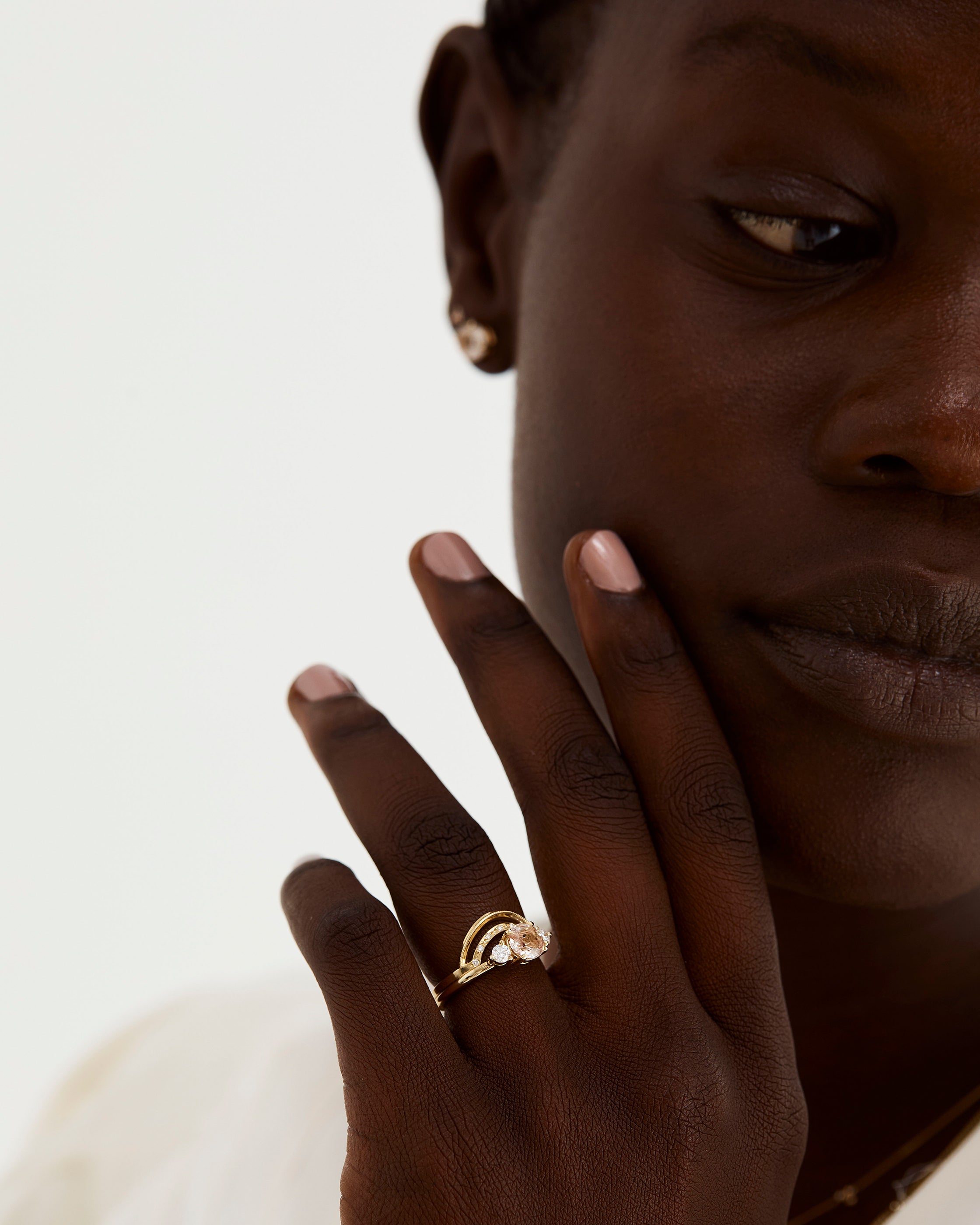 A model wears a double arc crown ring with diamonds stacked with a trio style engagement ring.