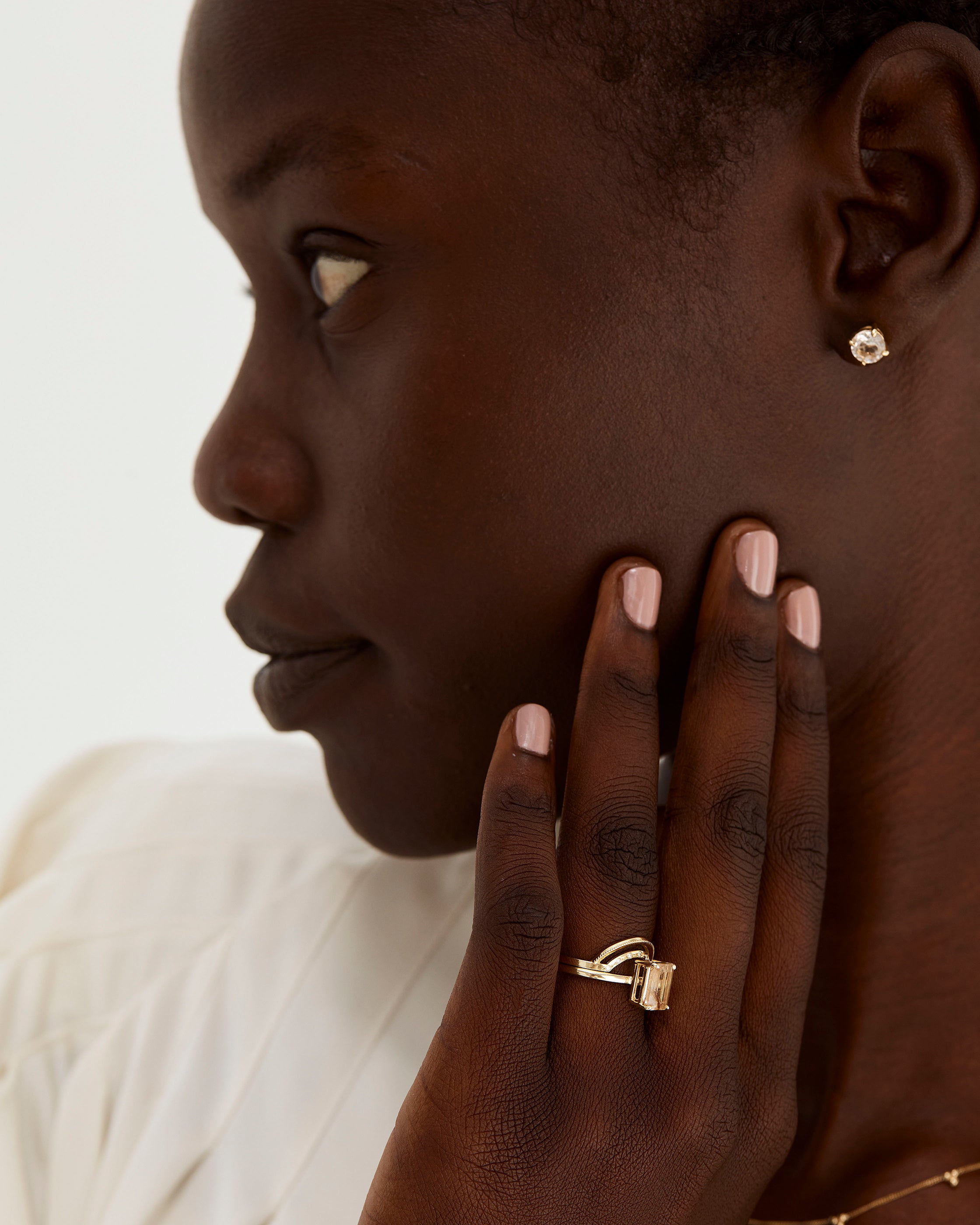 A model wears a double arc crown ring with diamonds stacked with an emerald cut solitaire style engagement ring.