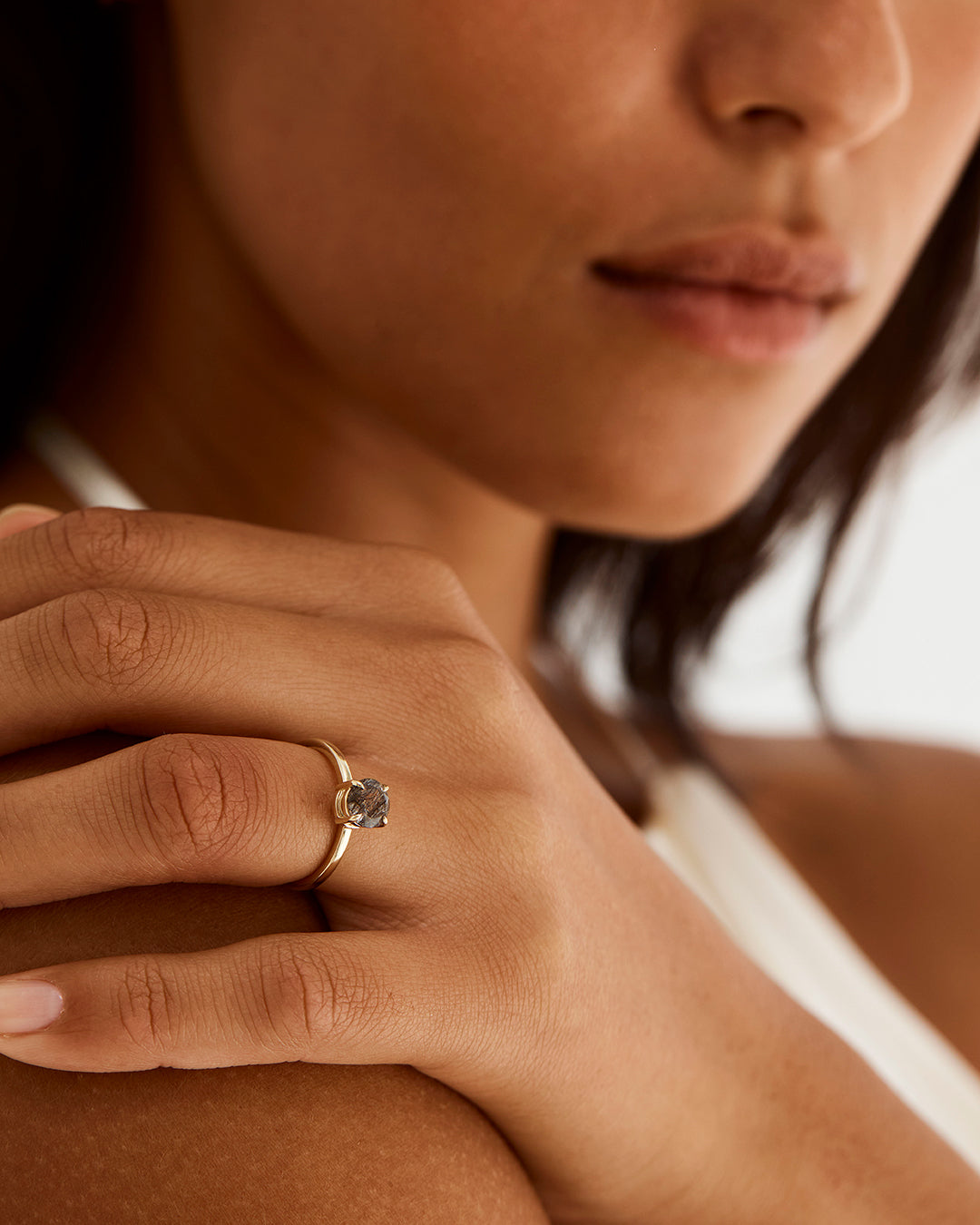 A model wears a round solitaire engagement ring with a tourmalinated quartz