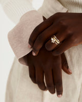 A cluster of seven white diamonds worn by a model as an engagement ring and stacked with an array of diamond and plain wedding bands.