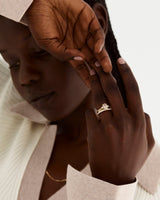 A model wears an oval rutilated quartz trio ring stacked with diamond and plain wedding bands